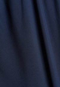 Tissu bleu foncé avec des plis doux et une surface lisse légèrement texturée. Pas de motifs ni d’objets visibles.
