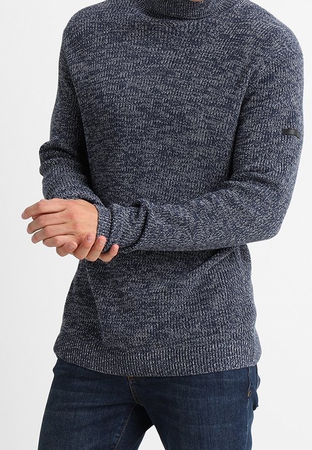 Granatowy sweter dzianinowy z wysokim kołnierzem, z teksturowanym wzorem i długimi rękawami. Zawiera mały czarny akcent z tkaniny na ramieniu.