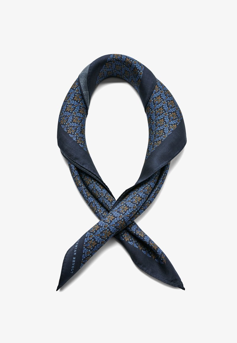 Foulard en soie marine présentant un motif floral géométrique en bleu et or, avec une texture lisse et des extrémités pointues. Croisé au centre.