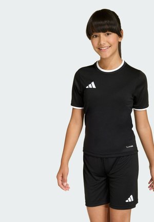 Crni sportski outfit s majicom kratkih rukava i kratkim hlačama. Sadrži bijele akcentne detalje i logo na prsima i na nozi. Izrađen je od rastezljivog materijala.