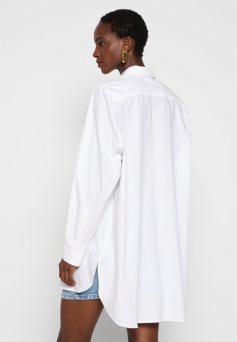 Witte blouse met lange mouwen, een puntige kraag, een rugplooitje en zijsplitten. Gemaakt van zachte stof met knoopmanchetten en een relaxte pasvorm.