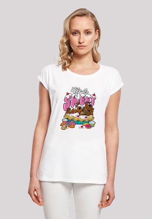 Weißes T-Shirt mit kurzen Ärmeln, das ein farbenfrohes Motiv zeigt: einen Hund auf einer Torte, umgeben von Gebäck. Der Text lautet "Das Leben ist süß."