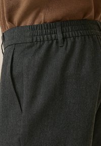 Pantalons grisonnants ajustés en tissu texturé, avec une taille élastique et des plis sur le devant. Le design met l'accent sur le confort et une silhouette élégante.