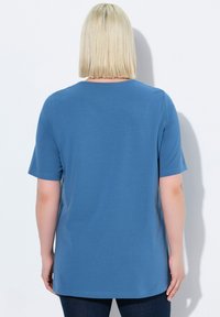 Modré tričko s krátkým rukávem z měkkého materiálu s volným střihem, s kulatým výstřihem a delším zadním lemem.