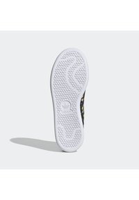 Bílá gumová podrážka tenisky s hexagonálním vzorem běhounu a logem Adidas, zobrazující část svršku s květinovým vzorem.