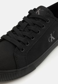 Zwarte canvas sneakers met tonale veters, platte rubberen zool en subtiele logo-details. Heeft een gestructureerde afwerking en ronde oogjes.