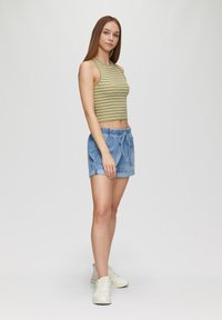 Gestreept groene crop top, denim shorts met elastische taille en trekkoord, lichtblauwe kleur, gecombineerd met witte sneakers.