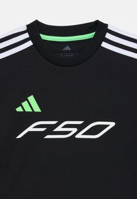 Melns sporta krekls ar baltu triju strīpu dizainu uz pleciem, zaļu akcentu apkakles iekšpusē un 'F50' logo baltā krāsā uz priekšpuses.