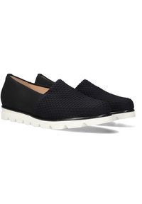 Zwarte instappers met een gestructureerde bovenkant met verhoogde stippen, een witte rubberen zool en een strak ontwerp. Geen veters of zichtbare hardware.