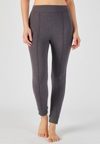 Leggings grises con una textura suave y detalles de costura. Los puños tienen un acento brillante y contraste en el dobladillo.