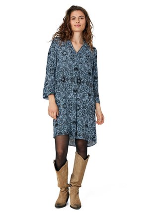 Abito blu con motivo floreale, scollatura a V e maniche a tre quarti, abbinato a stivali in suede marroni fino al ginocchio. Tessuto liscio e vestibilità comoda.