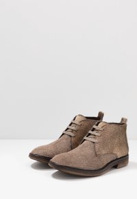 Bottines marron fabriquées en matériau texturé, avec un design à lacets, une finition subtile semblable à de la fourrure et un petit talon plat.