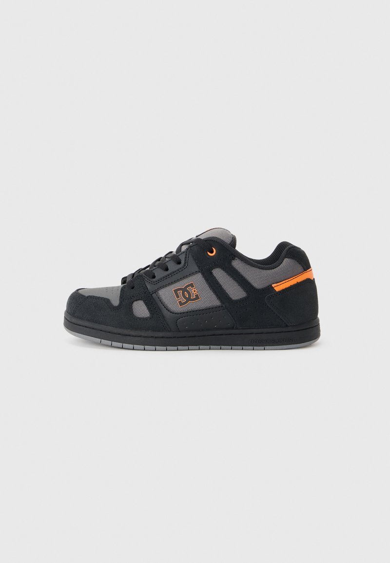 Zapatillas de skate en negro y gris con una parte superior de ante y malla, que presentan detalles en naranja, una puntera redonda y una suela de goma con detalles antideslizantes.