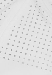 Tela blanca con perforaciones circulares pequeñas y espaciadas uniformemente en un patrón de cuadrícula, mostrando textura y detalles de costura.