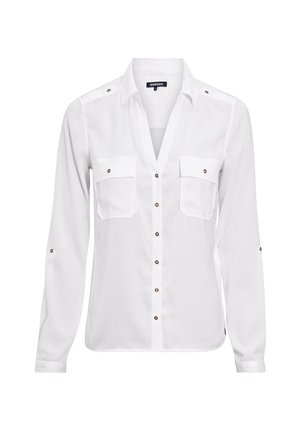 Camisa blanca de manga larga con botón delantero, dos bolsillos en el pecho y acentos en botones de bronce. Textura suave y diseño de cuello clásico.