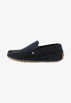 Scarpa slip-on in suede blu navy con punta arrotondata, dettagli cuciti, logo impresso e suola in gomma marrone chiaro con motivi antiscivolo.