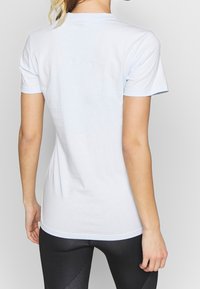 Camiseta de algodón azul claro con mangas cortas y cuello redondo, con una textura suave y un corte recto en el dobladillo.