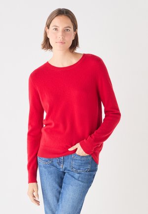 Roter Strickpullover mit Rundhalsausschnitt und langen Ärmeln, aus weichem Material, kombiniert mit blauen Jeans für einen lässigen Look.