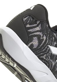 Schwarzer Sportschuh mit einer strukturierten Oberseite, die ein graues abstraktes Muster aufweist, weiße Zwischensohle und eine Gummiaußensohle mit Traktionsrillen.