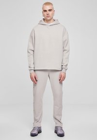 Beige oversized hoodie med snøre og matchende tapered bukser med knapdetaljer på siden. Båret med strukturerede grå sneakers.