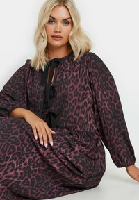 Leopardikuosi mekko tummanpurppuraisena ja mustana, jossa on pyöreä pääntie nauhoilla ja puffihihat. Pehmeä kangas, joka on virtaavan siluetin omaava.