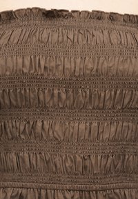 Καφέ ύφασμα με οριζόντιες σειρές από μαζευτές πιέτες ραμμένες ομοιόμορφα σε όλη την επιφάνεια, δημιουργώντας ένα υφασμάτινο, στρατς μοτίβο.