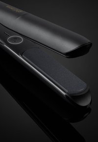 Zwarte haarstylers met een gladde bovenkant en een getextureerde keramische plaat. Is voorzien van een aan/uit-knop en heeft een slank ontwerp.