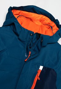 Blue winter jacket with orange fleece lining, front zipper, hood, and zippered chest pocket with orange pull cords.