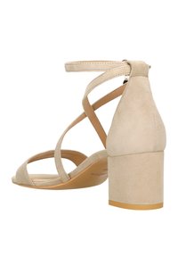 Beżowe zamszowe sandały na obcasie z krzyżującymi się paskami, zamkniętym tyłem i szerokim słupkowym obcasem. Gładka tekstura z minimalistycznym designem.