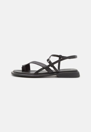 Schwarze Ledersandalen mit dünnen Riemen, offener Zehenpartie und flacher Sohle. Verstellbare Schnalle für einen sicheren Sitz. Einfaches und schlankes Design.