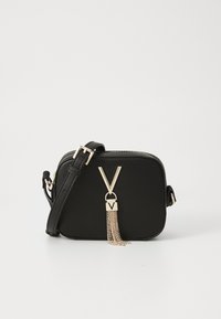 Svart rektangulär crossbody-väska med justerbar rem, gyllene dragkedja och dekorativt guld V-format emblem med hängande kedjor.