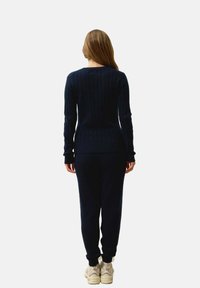 Pull en maille côtelée bleu marine à manches longues, associé à un pantalon de jogging assorti. Texture douce et design ajusté, avec un col rond.