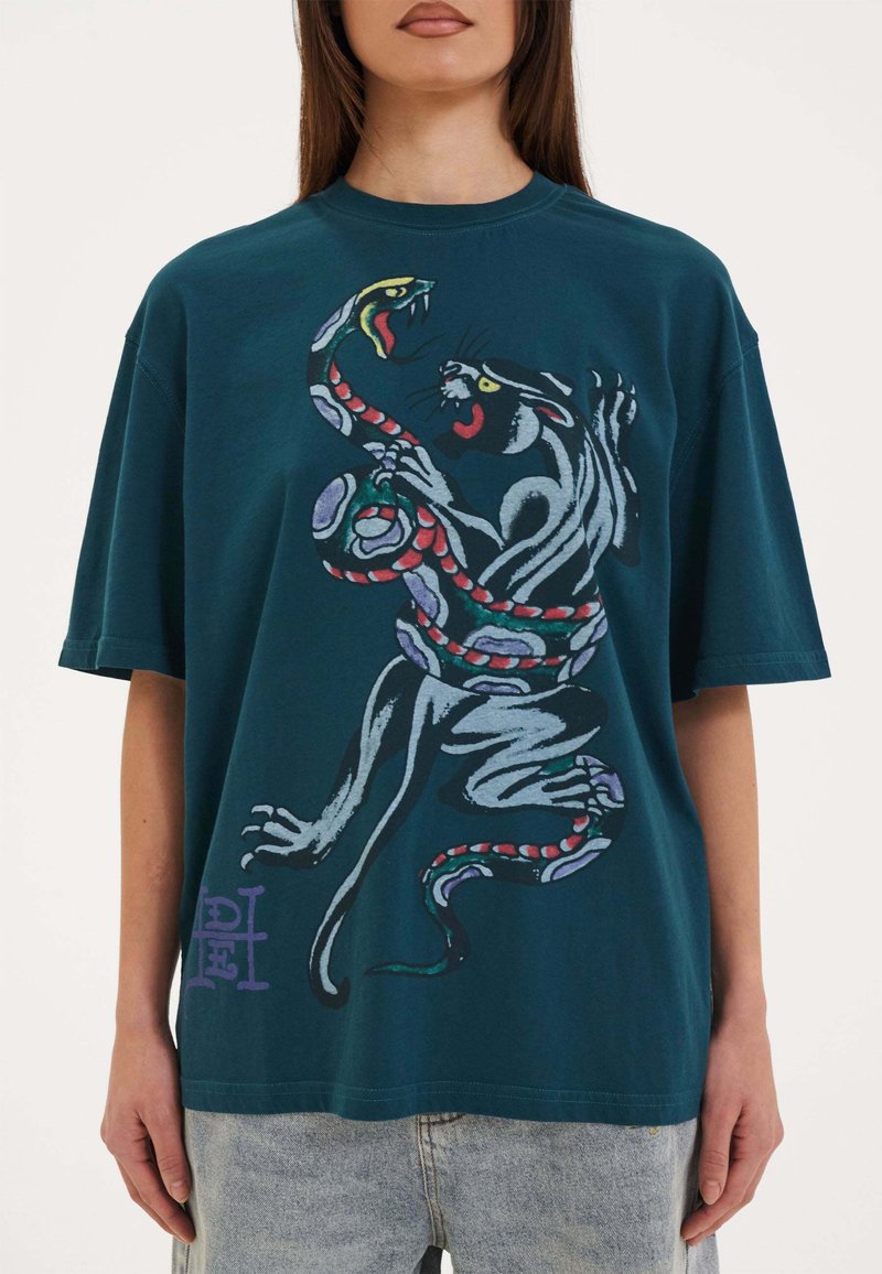 Overdimensioneret teal bomulds T-shirt med farverig grafik af en panter, der er snoet sammen med en slange. Rund halsudskæring med korte ærmer.