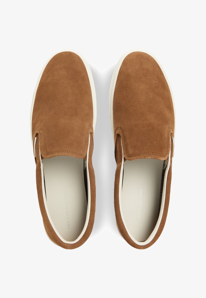 Paire de chaussures en suède marron à enfiler avec semelles en caoutchouc blanches, vues de dessus sur fond blanc.
