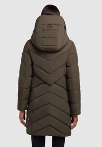 Olivroheline puffjakke, millel on laineline tikandi disain, suur kapuuts ja küljetaskud. Materjal näib olevat veekindel ja polsterdatud.