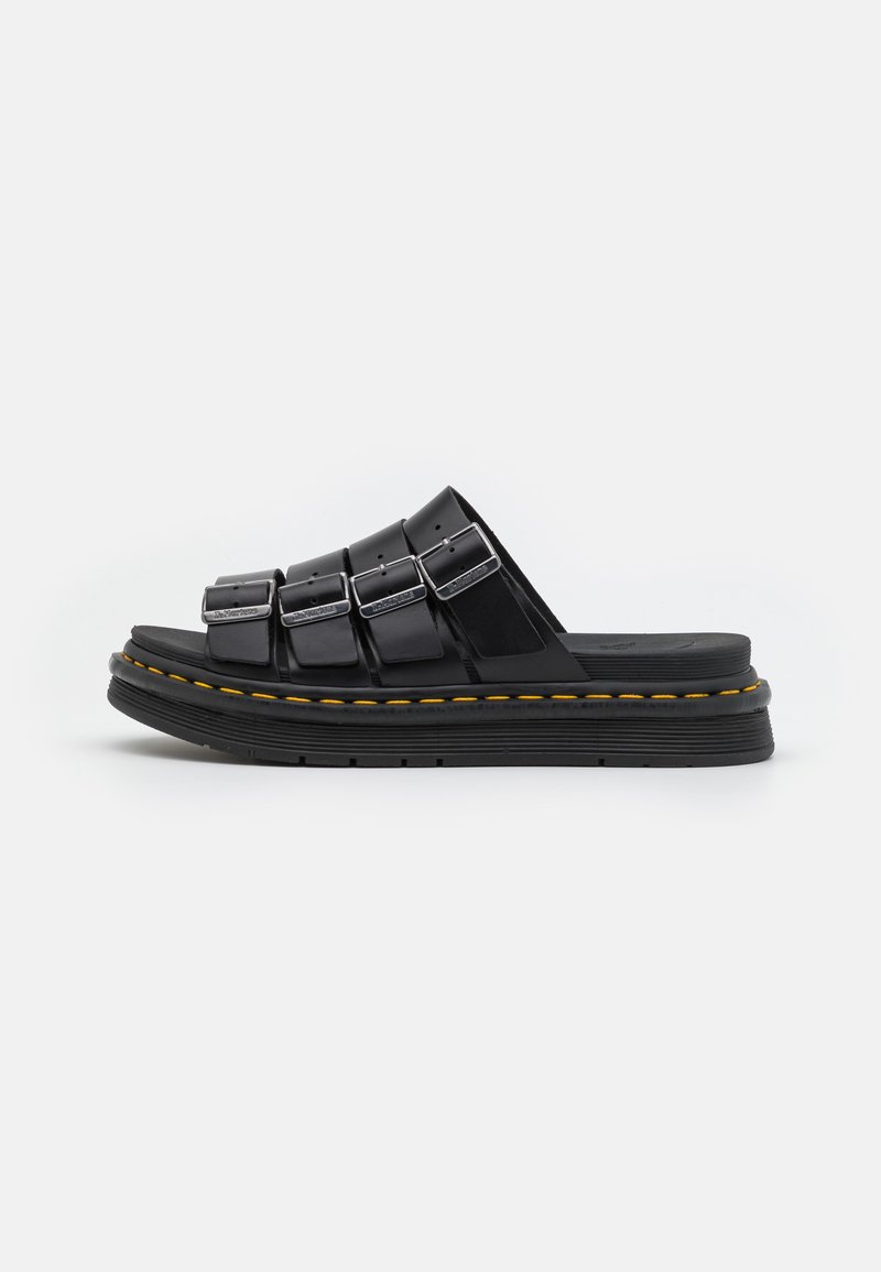 Black slide sandals with multiple straps, silver buckles, and a thick rubber sole featuring yellow stitching accents.