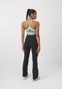 Light blue sports bra with a cutout back detail paired with black flared leggings. Both made from stretchy fabric for flexibility and comfort.