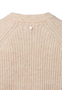 Beige gestrickter Pullover mit geripptem Kragen und detaillierter Texturstichung, der einen kleinen runden Knopf mit geschwungenen Buchstaben in der Nähe des Ausschnitts aufweist.