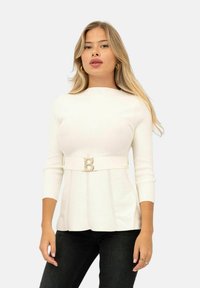 Top bianco aderente con scollatura rotonda e maniche a tre quarti. Presenta un orlo a peplo e una cintura con una fibbia dorata a forma di "B".