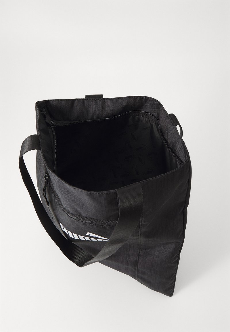 Borsa a tracolla in tessuto nero di forma rettangolare, con chiusura a zip superiore, manici robusti e logo stampato sulla parte anteriore. L'interno è foderato.