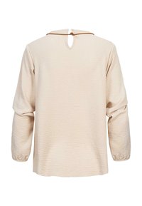 Lichtbeige longsleeve top van een gestructureerde stof, met een kleine keyhole-opening aan de achterkant en een gestrikt accent. Losse pasvorm met elastische manchetten.