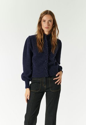 Navyblauer gestrickter Cardigan mit hohem Kragen, Knopfleiste und strukturiertem Finish. Verfügt über puffige Ärmel und einen gerippten Taillenbund.