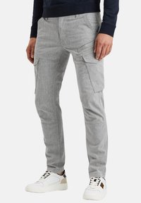 Pantalones cargo de color gris claro con bolsillos laterales, fabricados en una tela texturizada. Diseñados con un ajuste ceñido y combinados con zapatillas blancas.