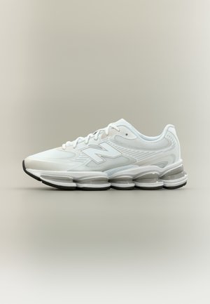 Weißer athletischer Sneaker mit Mesh-Obermaterial, Schnürdesign und segmentierter luftgepolsterter Sohle auf neutralem Hintergrund.
