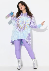 Světle modré a levandulové tie-dye mikinové šaty s designem zlatého slunečního výbuchu; spárováno s fialovými legínami a stříbrnými kotníkovými botami.