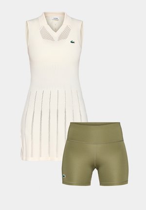 Sleeveless cream polo dress with textured stripes and a green logo, paired with olive green athletic shorts featuring a fitted waistband.