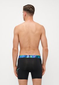 Zwarte zwembroek met een kleurrijke, abstracte patroonstrip aan de taille. Het materiaal lijkt glad en aansluitend, ontworpen voor atletisch gebruik.