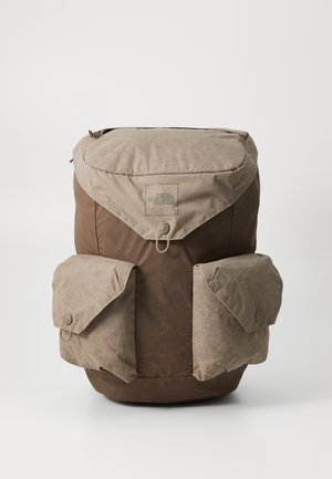 Sac à dos North Face marron et beige avec rabat supérieur et deux poches avant, chacune sécurisée par un rabat à bouton.