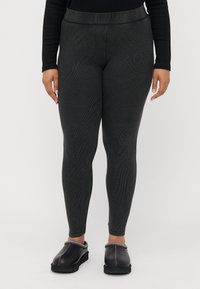 Magas derékig érő, sötétszürke leggings bordázott textúrával. Fekete, slip-on cipővel párosítva, kontrasztos varrással az élén.