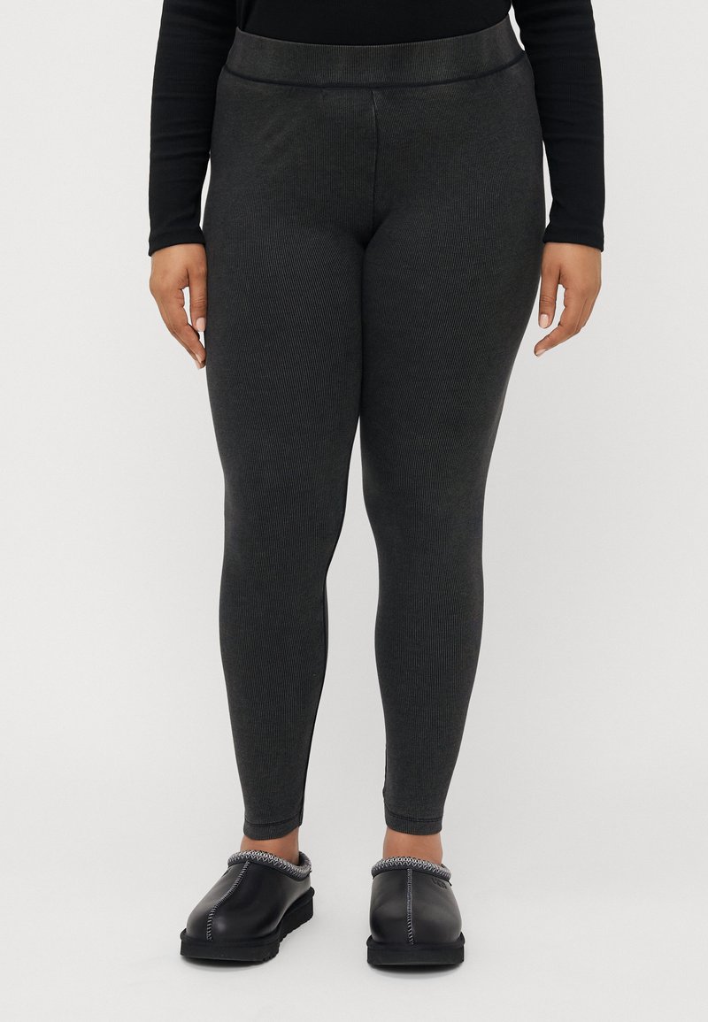 Magas derékig érő, sötétszürke leggings bordázott textúrával. Fekete, slip-on cipővel párosítva, kontrasztos varrással az élén.